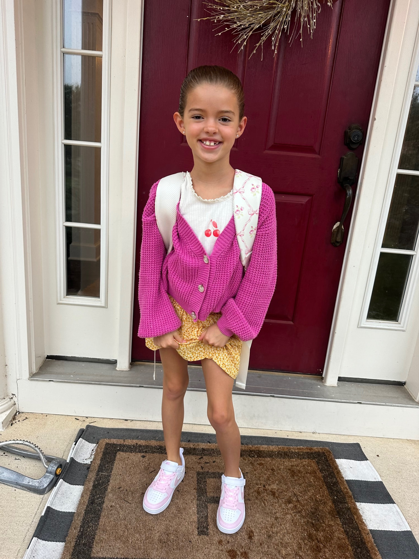 Paige Fitzer smiling on the front porch in a pink cardigan